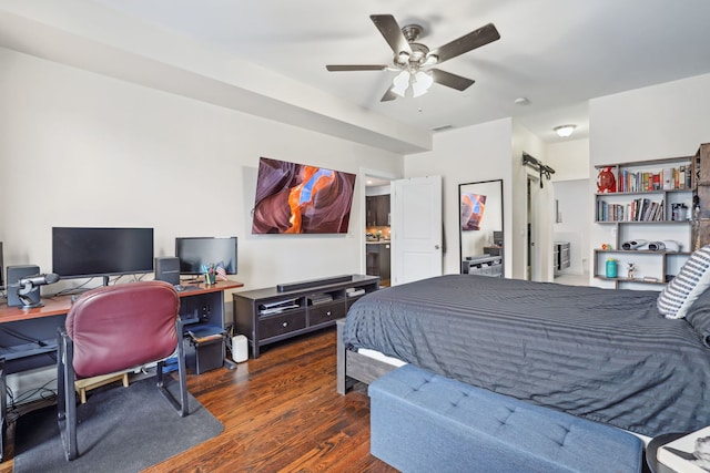 bedroom with a barn door, visible vents, ceiling fan, and wood finished floors