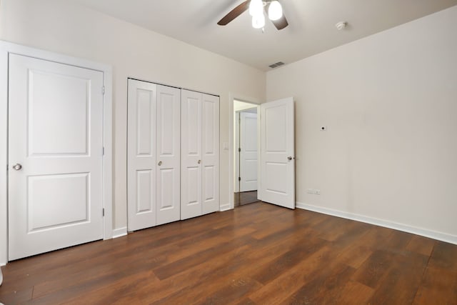 unfurnished bedroom with dark wood-style floors, a closet, a ceiling fan, and baseboards