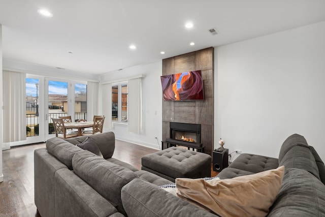 living room featuring dark wood-style flooring, plenty of natural light, a tile fireplace, and recessed lighting