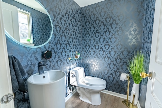 bathroom featuring toilet, wallpapered walls, baseboards, and wood finished floors