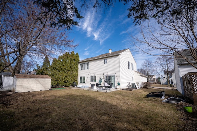 rear view of house featuring a lawn, an outdoor structure, a chimney, and a patio