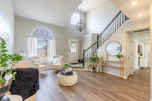 foyer entrance featuring visible vents, stairway, an inviting chandelier, and wood finished floors