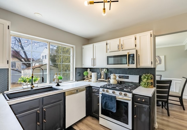 kitchen with stainless steel gas stove, white cabinets, dishwasher, light countertops, and a sink