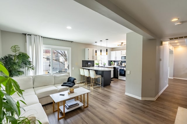 living room featuring baseboards, visible vents, dark wood-type flooring, and recessed lighting