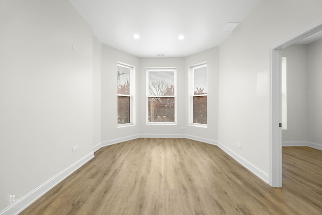 spare room featuring light wood finished floors, recessed lighting, and baseboards