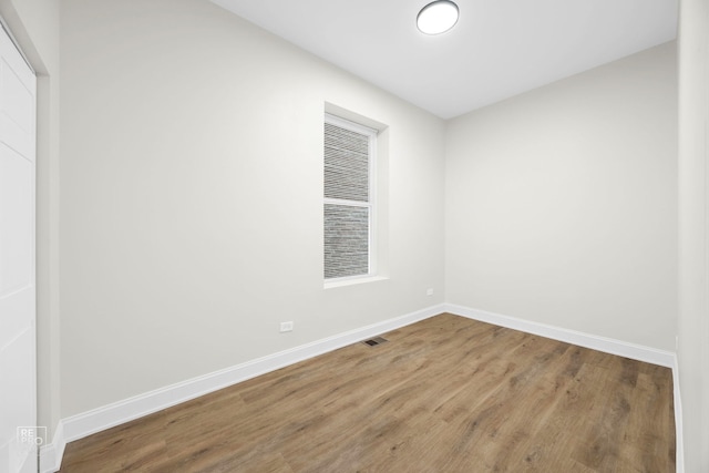 unfurnished room featuring visible vents, baseboards, and wood finished floors