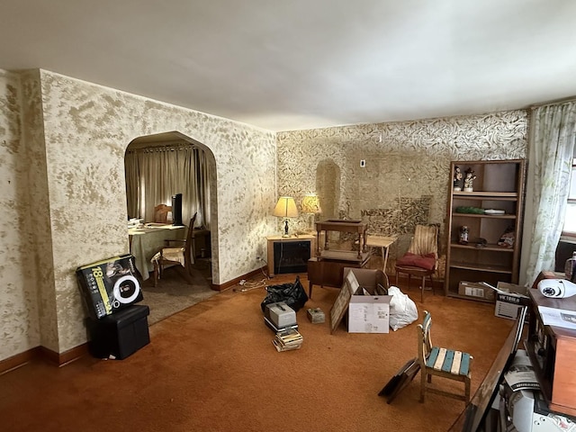 interior space featuring carpet floors, arched walkways, baseboards, and wallpapered walls