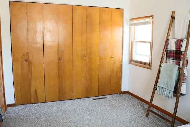 unfurnished bedroom featuring light carpet, a closet, visible vents, and baseboards