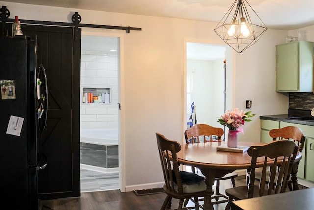 dining room with a notable chandelier, a barn door, dark wood-type flooring, and baseboards