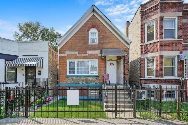 view of front facade with a fenced front yard, a gate, and brick siding