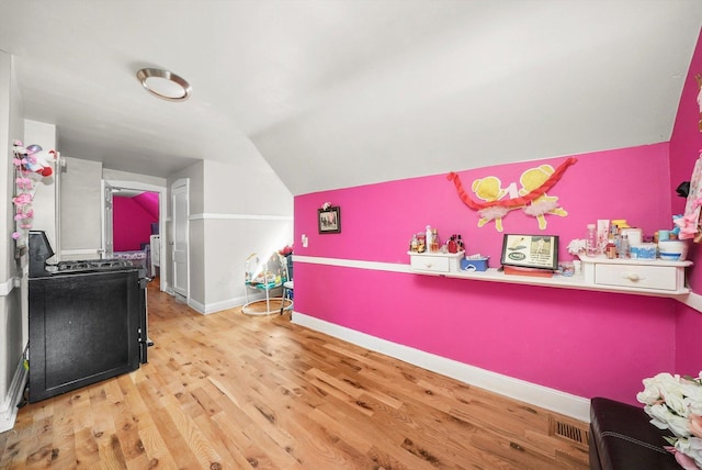 interior space featuring light wood-type flooring, visible vents, baseboards, and vaulted ceiling
