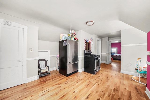 kitchen with lofted ceiling, stainless steel appliances, light wood finished floors, and baseboards