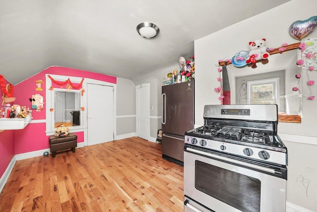 kitchen featuring vaulted ceiling, baseboards, stainless steel appliances, and wood finished floors