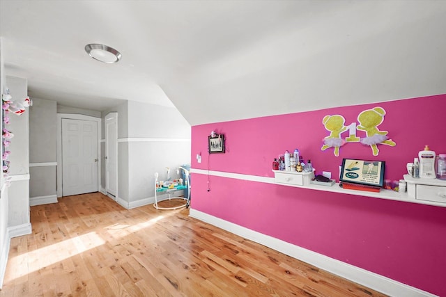 interior space featuring lofted ceiling, baseboards, and wood finished floors