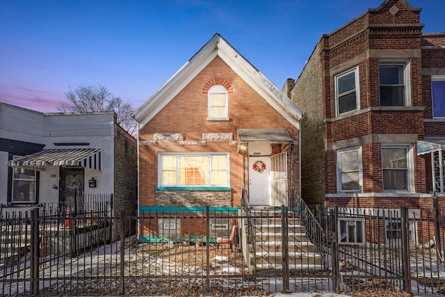 view of front facade featuring brick siding and a fenced front yard