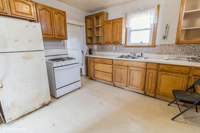 kitchen with a sink, white appliances, brown cabinetry, and light floors