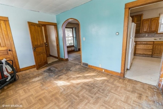 interior space featuring baseboards, visible vents, and arched walkways