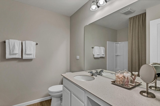 full bath featuring toilet, vanity, visible vents, baseboards, and walk in shower