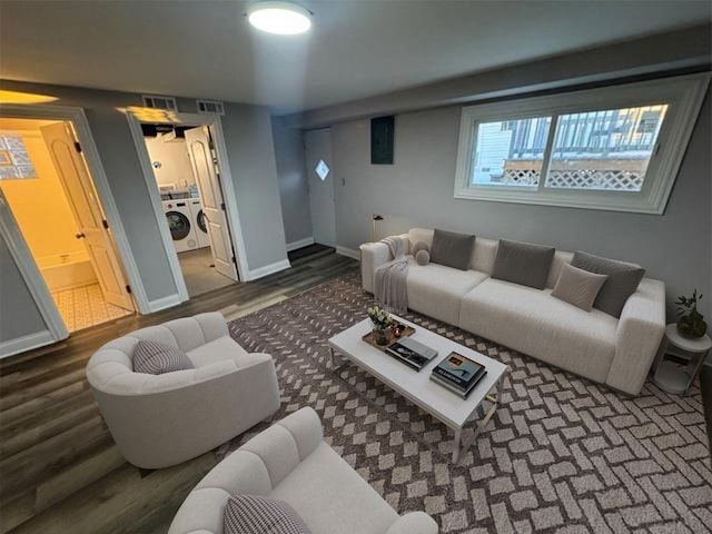 living room featuring separate washer and dryer, dark wood-style flooring, and baseboards