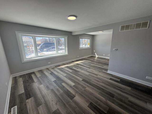 spare room with baseboards, visible vents, and dark wood finished floors