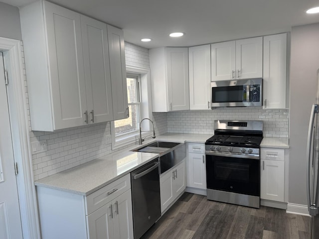 kitchen with stainless steel appliances, white cabinets, a sink, and dark wood-style floors