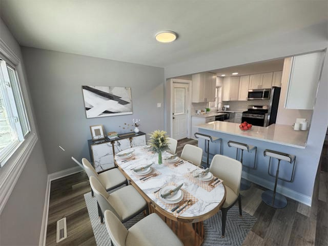 dining area with dark wood-type flooring and baseboards