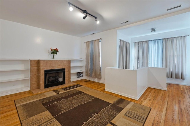 living area with visible vents, wood finished floors, and a tile fireplace