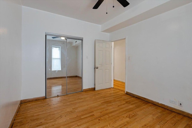 unfurnished bedroom with light wood-style floors, a closet, baseboards, and a ceiling fan