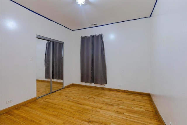 spare room featuring visible vents, baseboards, and wood finished floors