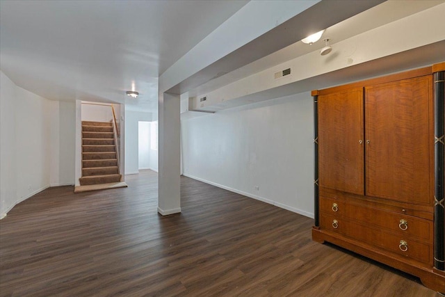 finished basement with dark wood-style flooring, visible vents, stairway, and baseboards