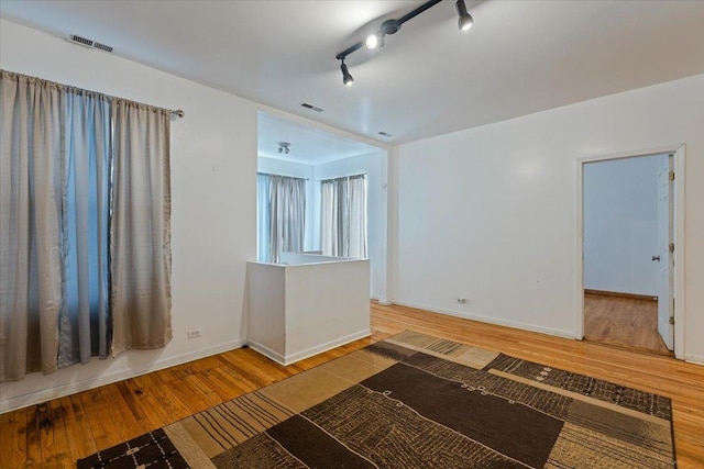 unfurnished room with baseboards, visible vents, and wood finished floors