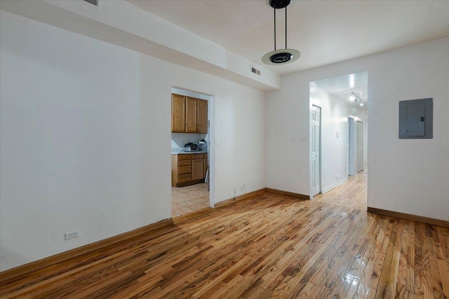 interior space with visible vents, light wood-style flooring, electric panel, and baseboards