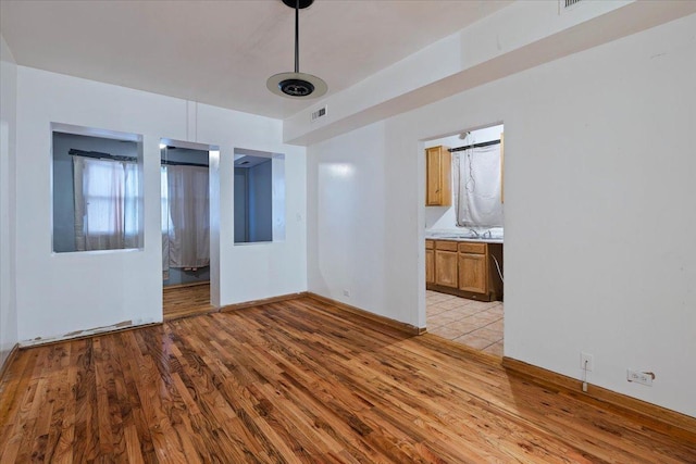 unfurnished room featuring light wood-type flooring, baseboards, and visible vents