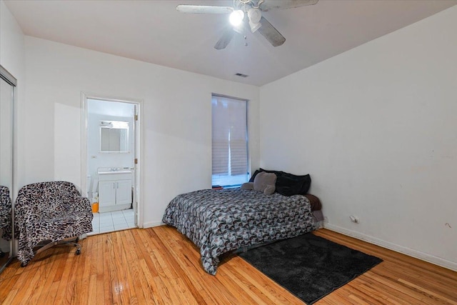 bedroom with visible vents, ensuite bathroom, baseboards, and wood finished floors