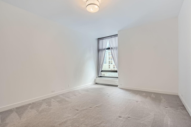 empty room featuring baseboards and light carpet