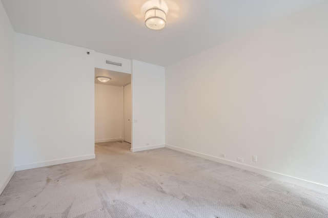 unfurnished room with baseboards, visible vents, and light carpet