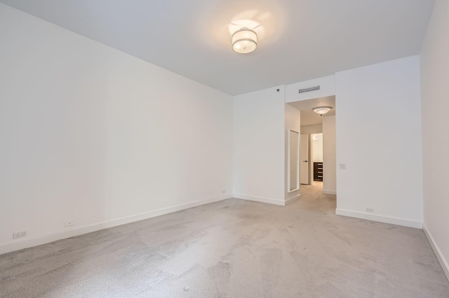 empty room featuring baseboards, visible vents, and light carpet