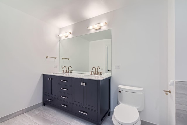 full bath featuring double vanity, baseboards, toilet, and a sink