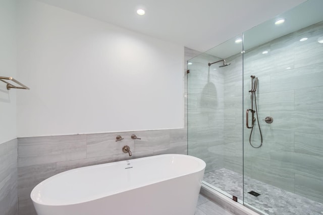 bathroom with a soaking tub, recessed lighting, tile walls, and tiled shower