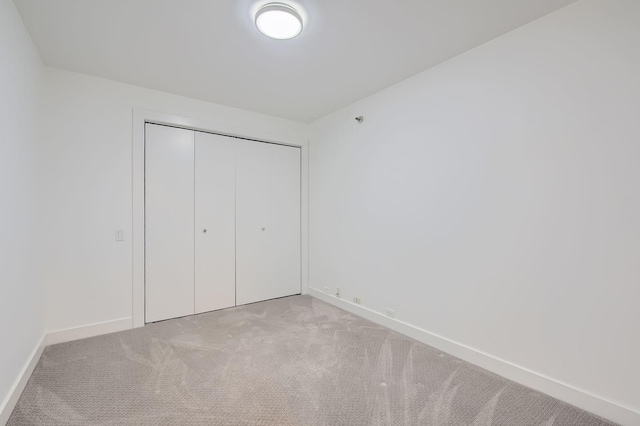 unfurnished bedroom featuring carpet flooring, baseboards, and a closet