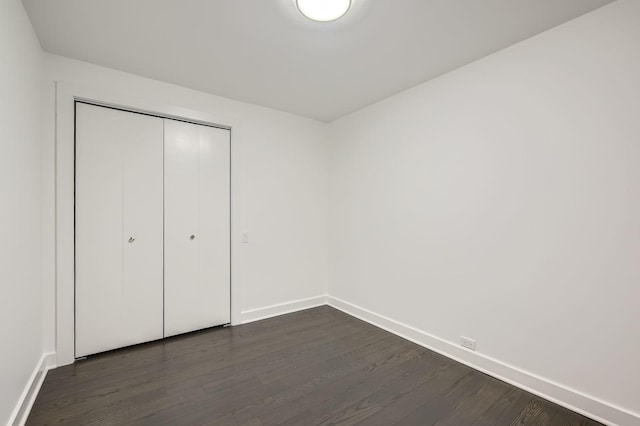 unfurnished bedroom featuring a closet, baseboards, and dark wood-style flooring