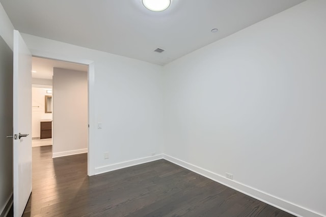 unfurnished room featuring visible vents, baseboards, and dark wood-style flooring