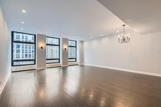 spare room with recessed lighting, a chandelier, baseboards, and dark wood-style floors