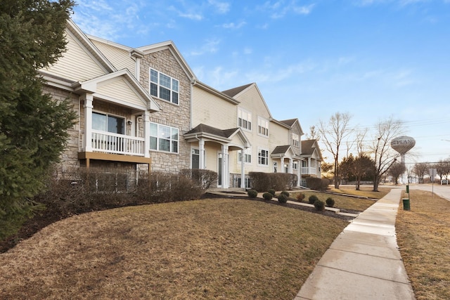 view of side of property with stone siding and a yard