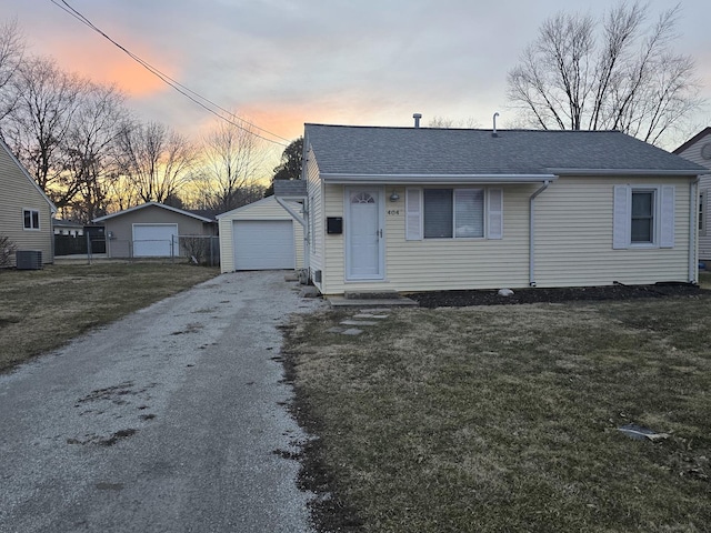 view of front of home featuring cooling unit, an outdoor structure, a detached garage, driveway, and a front yard