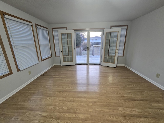 spare room with french doors, baseboards, and wood finished floors