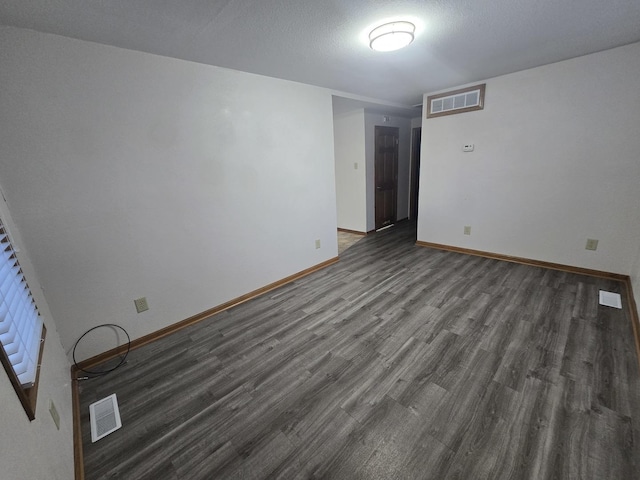 unfurnished room featuring visible vents, a textured ceiling, baseboards, and wood finished floors