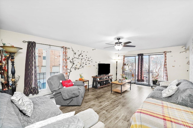 living area with plenty of natural light, wood finished floors, and a ceiling fan