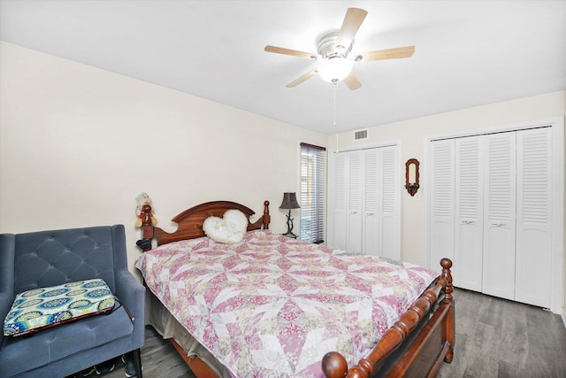 bedroom with a ceiling fan, visible vents, dark wood-type flooring, and multiple closets