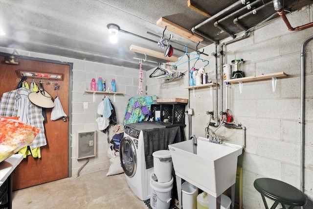 laundry room with a sink, laundry area, washing machine and clothes dryer, and concrete block wall